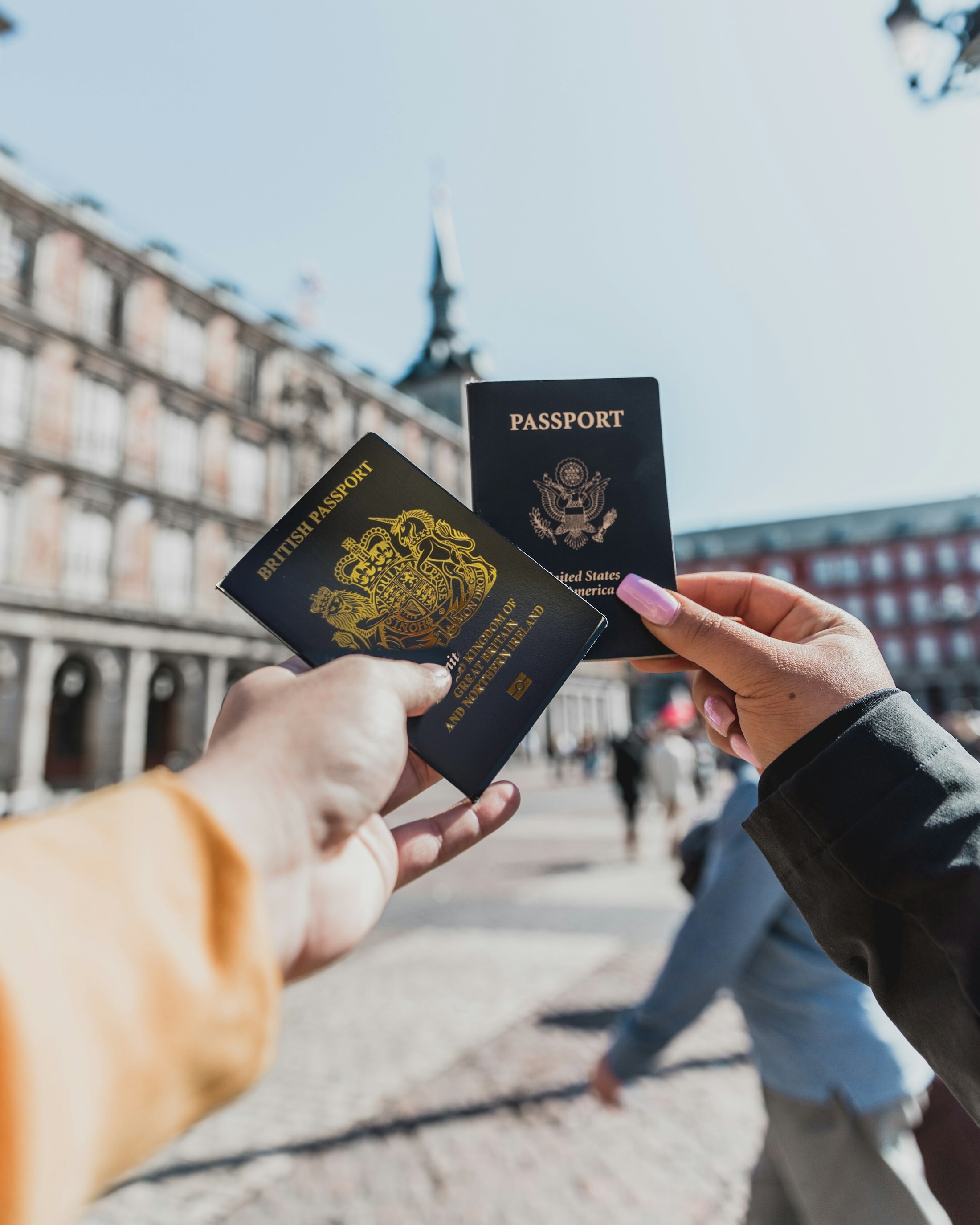 British passport in front of an American passport, held by travellers